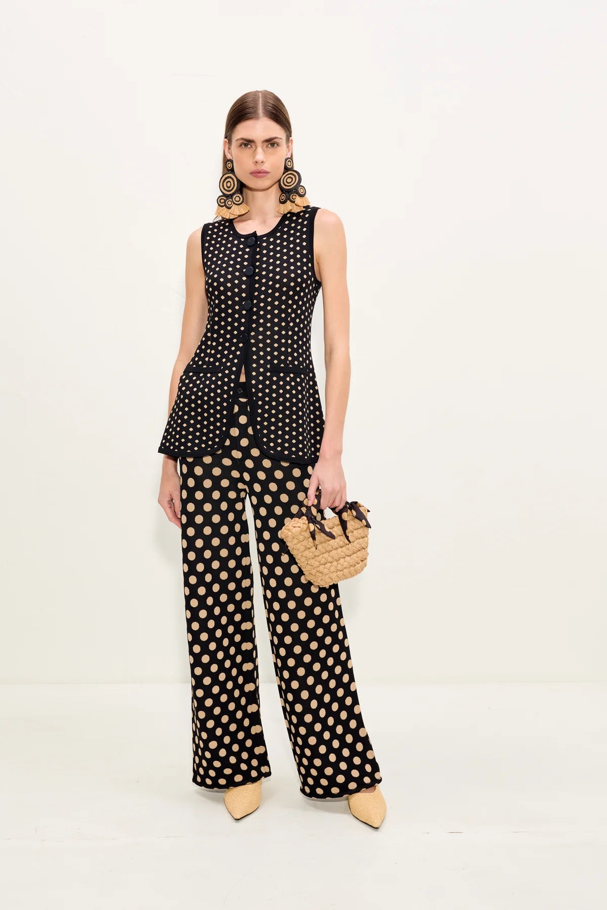 Woman wearing a black and tan polka dot outfit with wide-leg pants on a white background