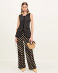 Woman wearing a black and tan polka dot outfit with wide-leg pants on a white background