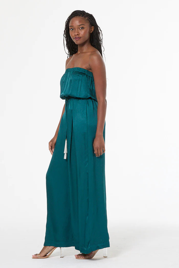Woman wearing a teal strapless jumpsuit on a white background