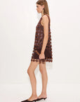 A woman modeling a sleeveless brown crochet lace mini dress with a scalloped hem, paired with dark brown pointed-toe flats, against a plain white studio background.