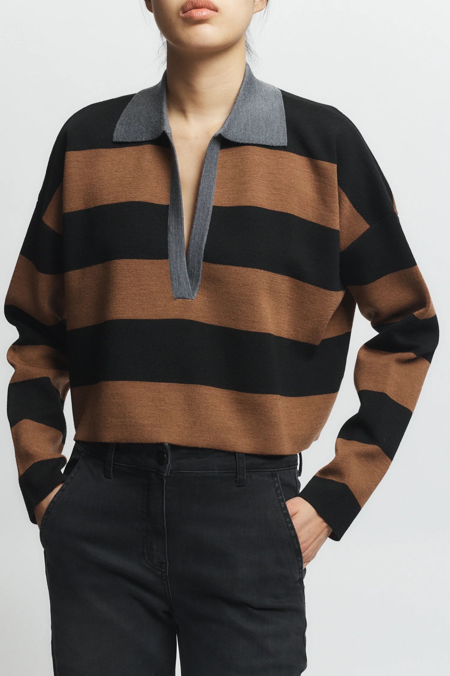 Person wearing a brown and black striped sweater with a gray collar on a white background