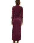 A model shown from the back wearing a long-sleeve turtleneck top and matching maxi skirt set in a deep burgundy color, featuring textured side panels, on a solid white background.