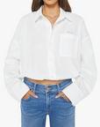 A woman modeling a white cropped button-up shirt with a chest pocket and light blue jeans against a plain white studio background.