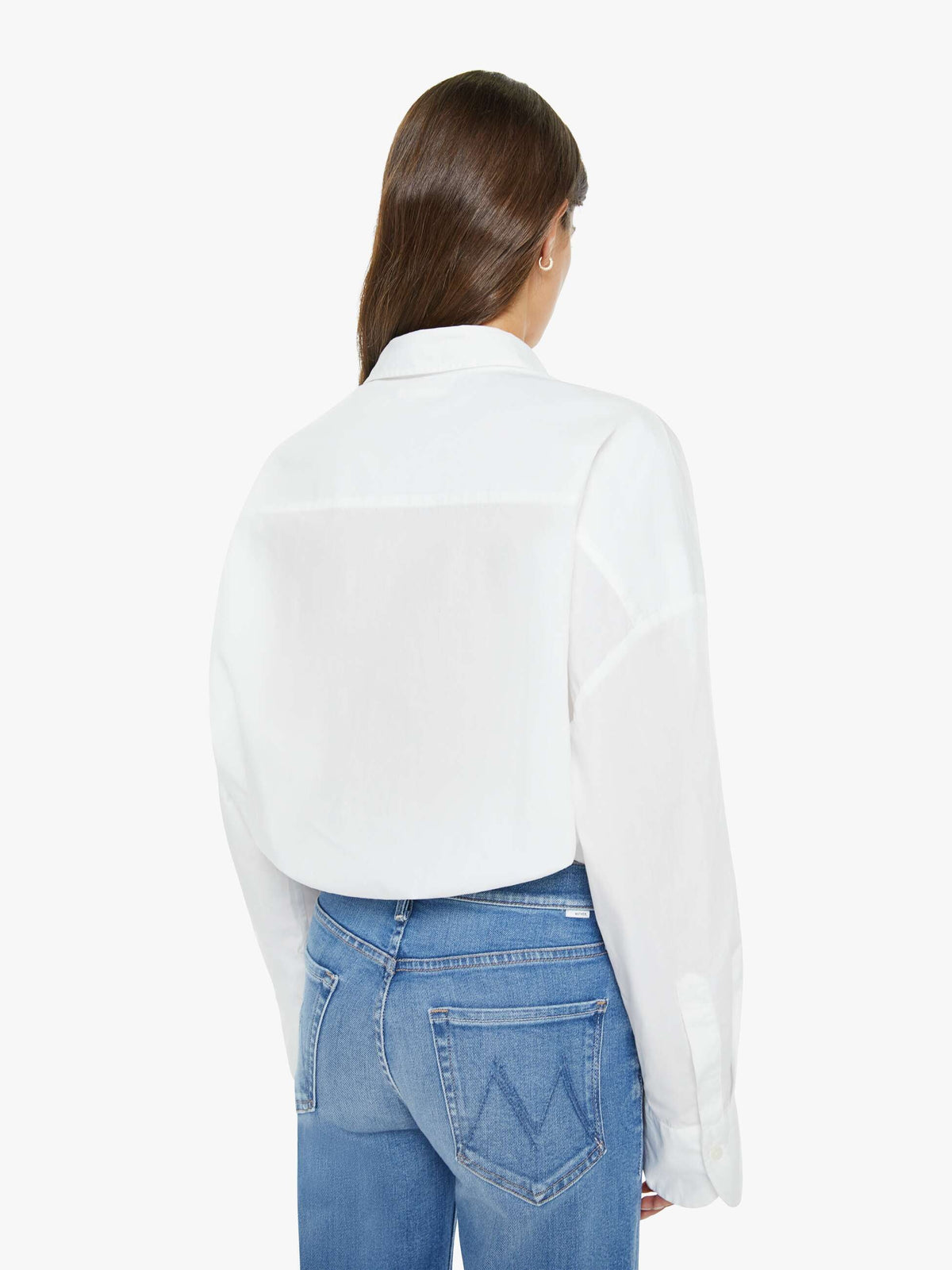 Person wearing a white shirt and blue jeans on a plain background
