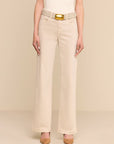 A model wearing beige wide-leg cropped pants with a matching textured belt featuring a gold buckle, styled with a white top and tan heels against a solid beige background.