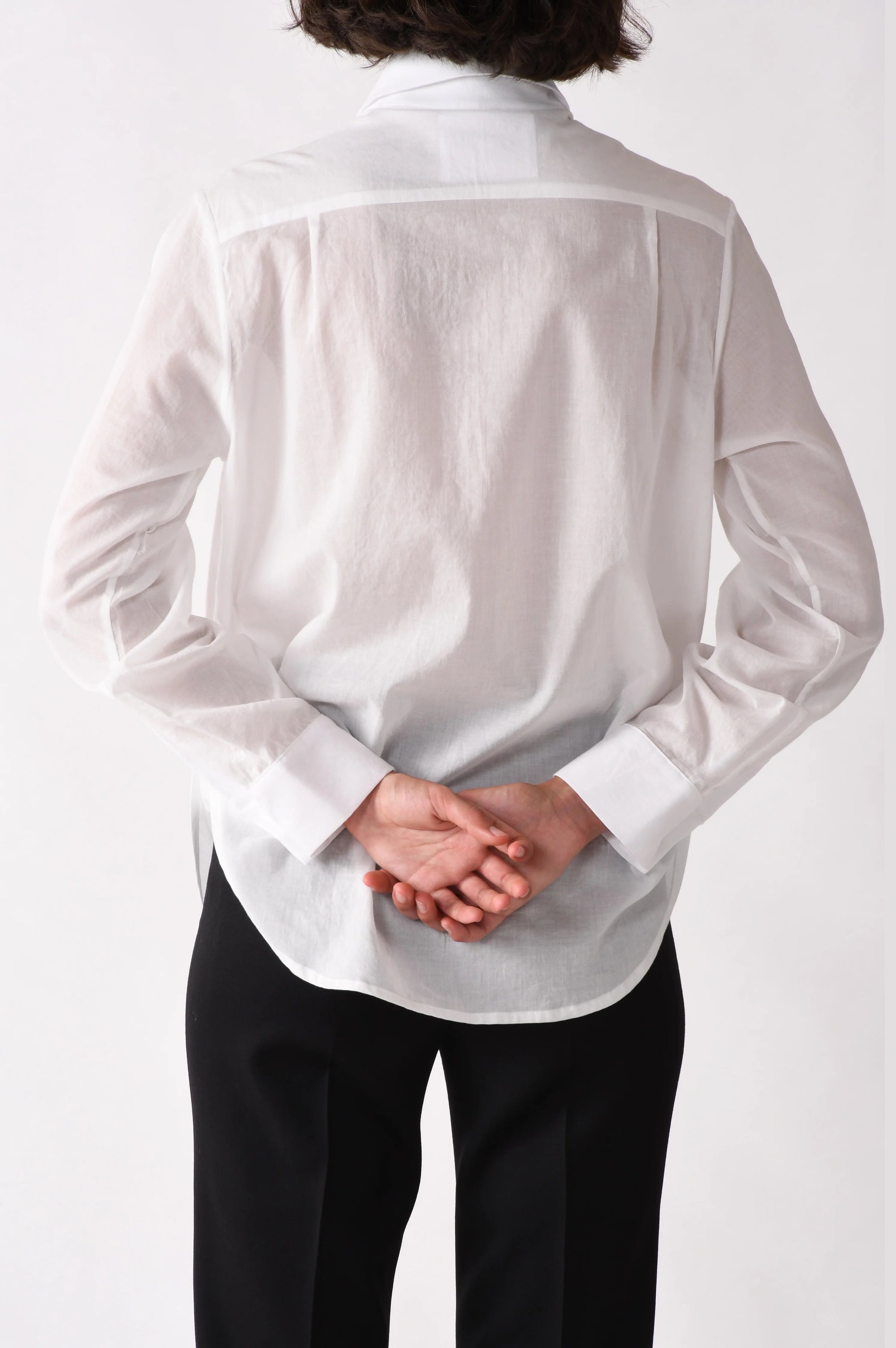 Person wearing a white shirt and black pants on a white background