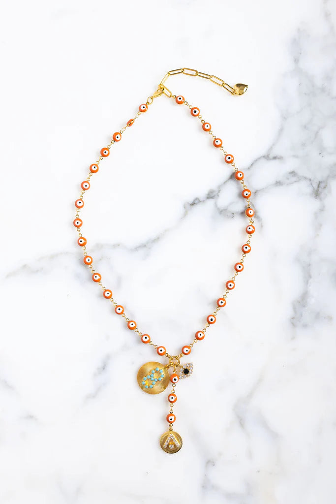 Necklace with orange beads and gold accents on a marble background