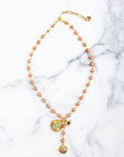 Necklace with orange beads and gold accents on a marble background