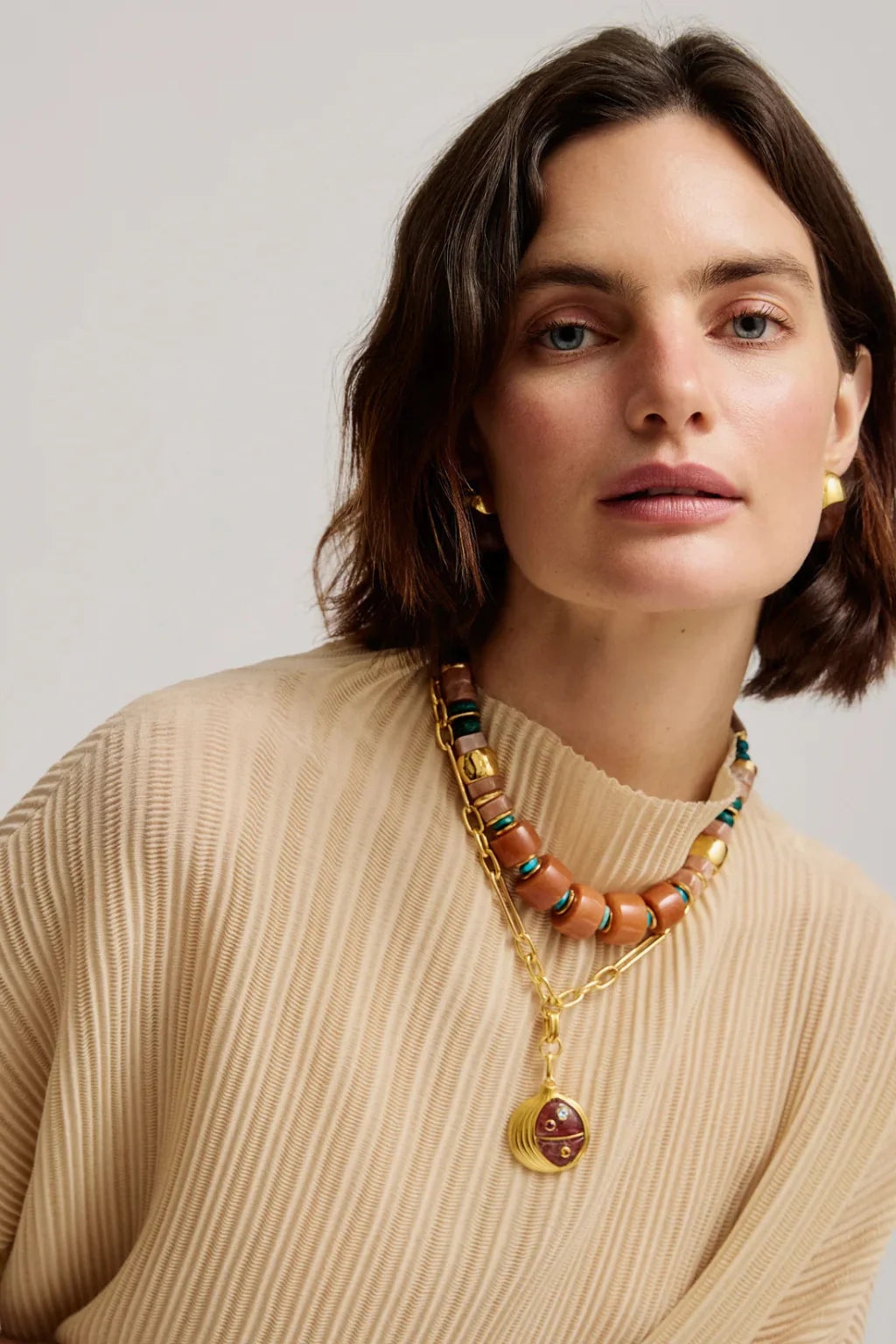 Woman wearing a beaded necklace with a neutral background