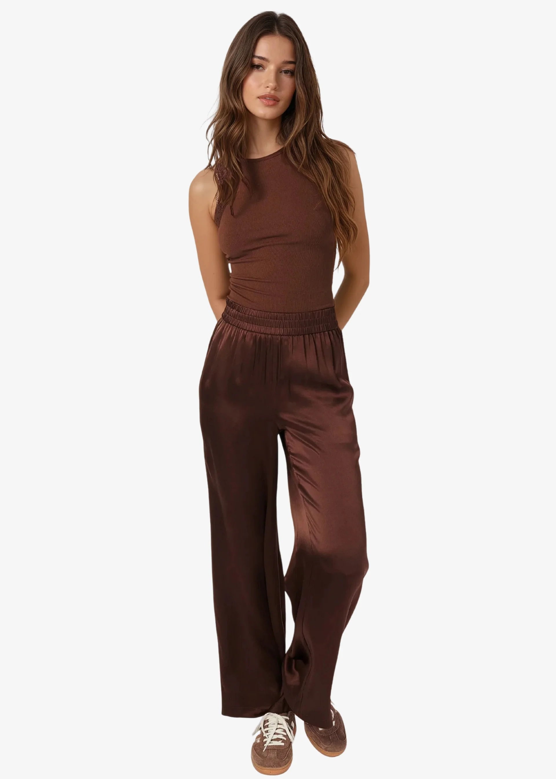 Woman wearing a brown sleeveless top and wide-leg pants on a white background