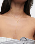 Gold necklace worn by a person on a plain background