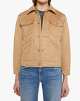 A model wearing a tan suede jacket with silver studded details, paired with blue jeans and sunglasses, against a plain white background.