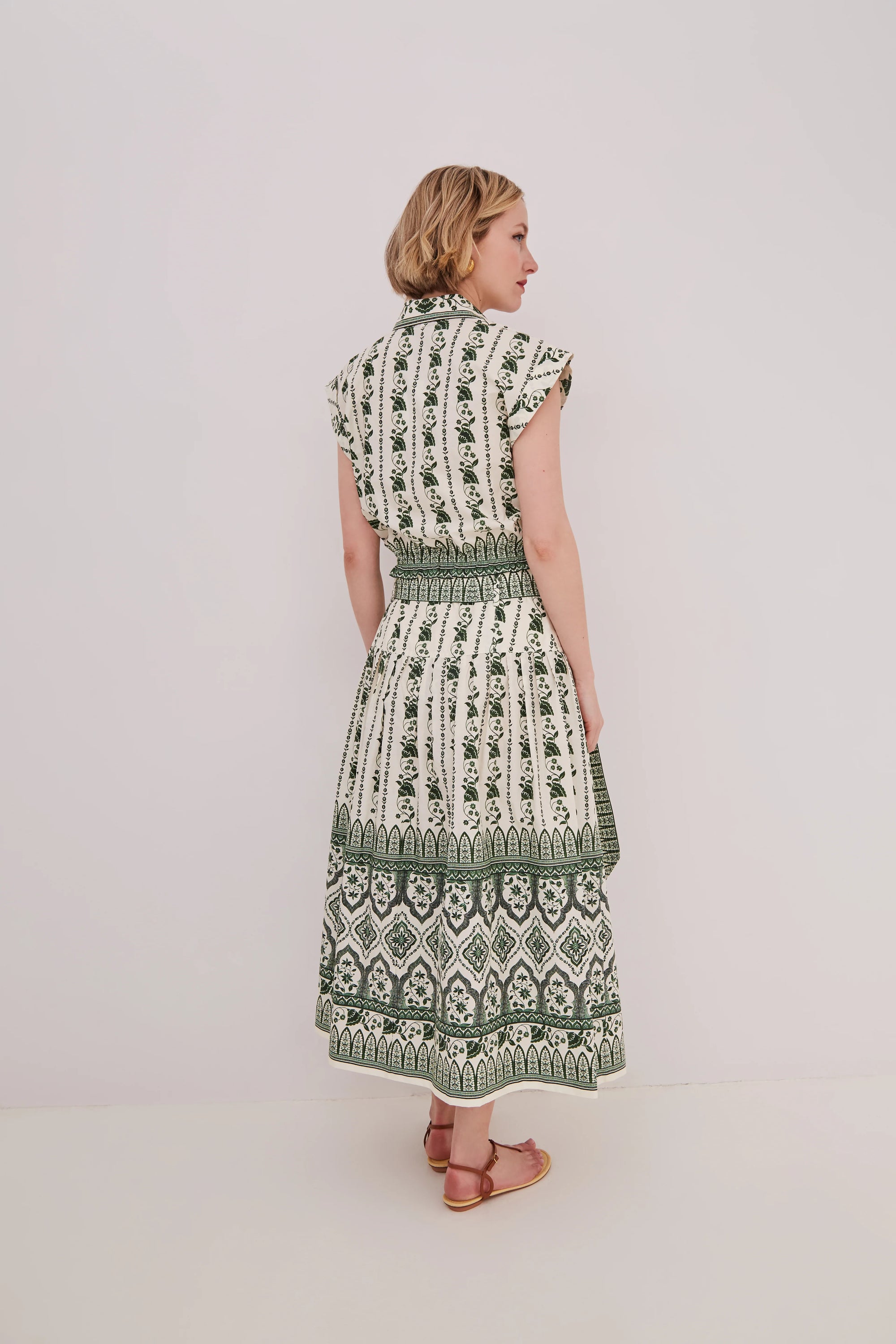 Woman wearing a green and white patterned matching set on a plain background