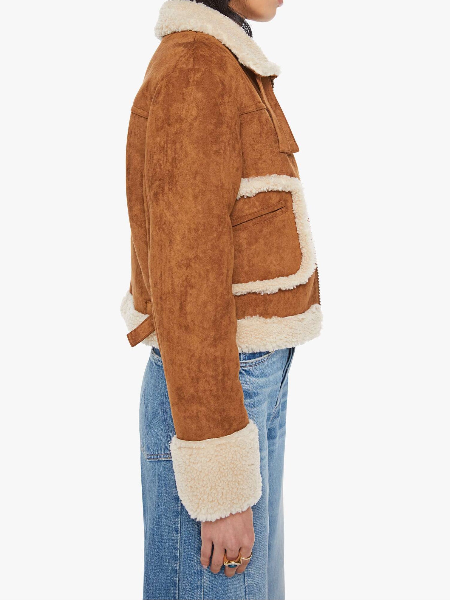 Person wearing a brown jacket with white fur trim on a white background