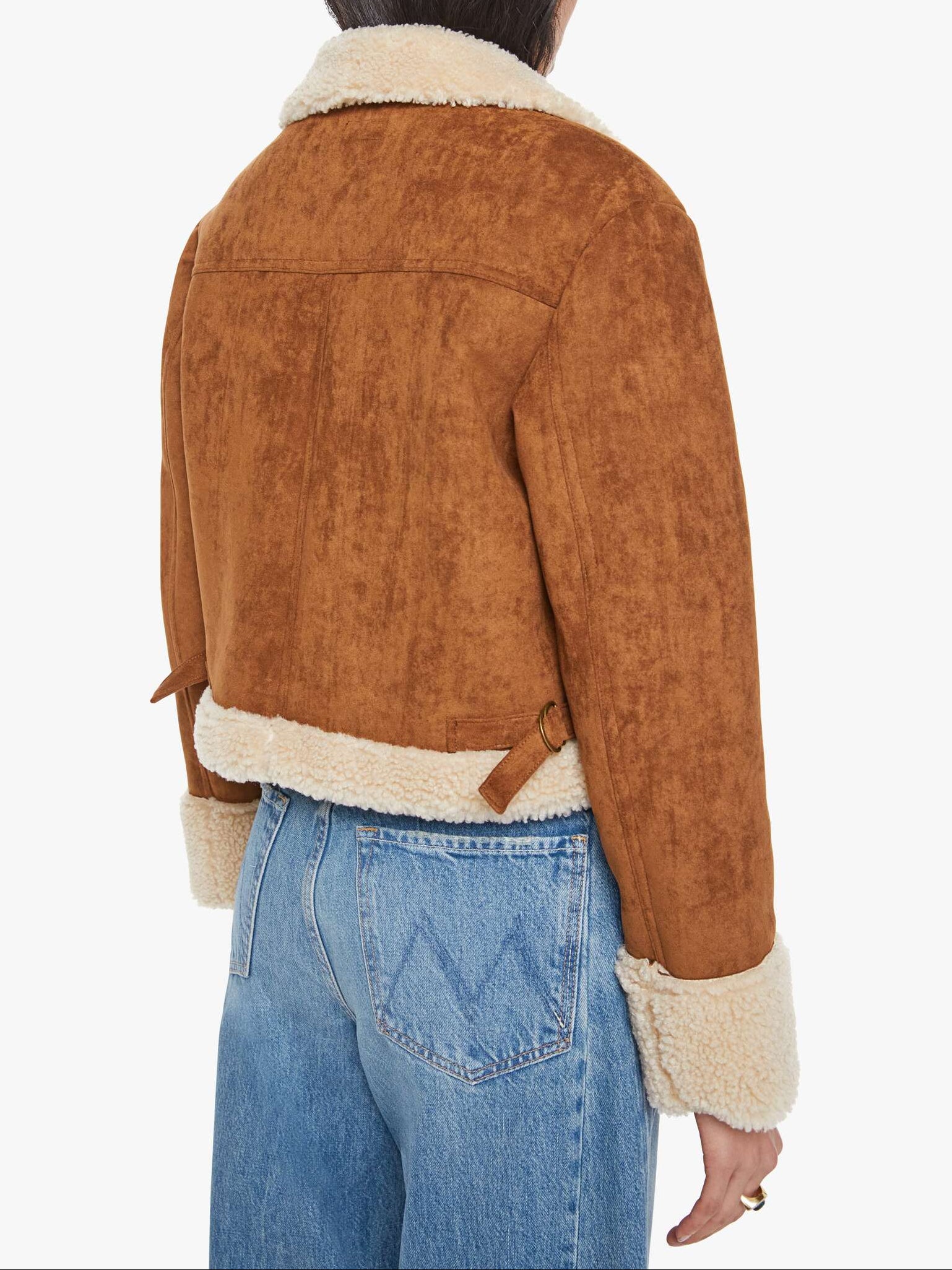 Person wearing a brown suede jacket with white fur lining on a white background