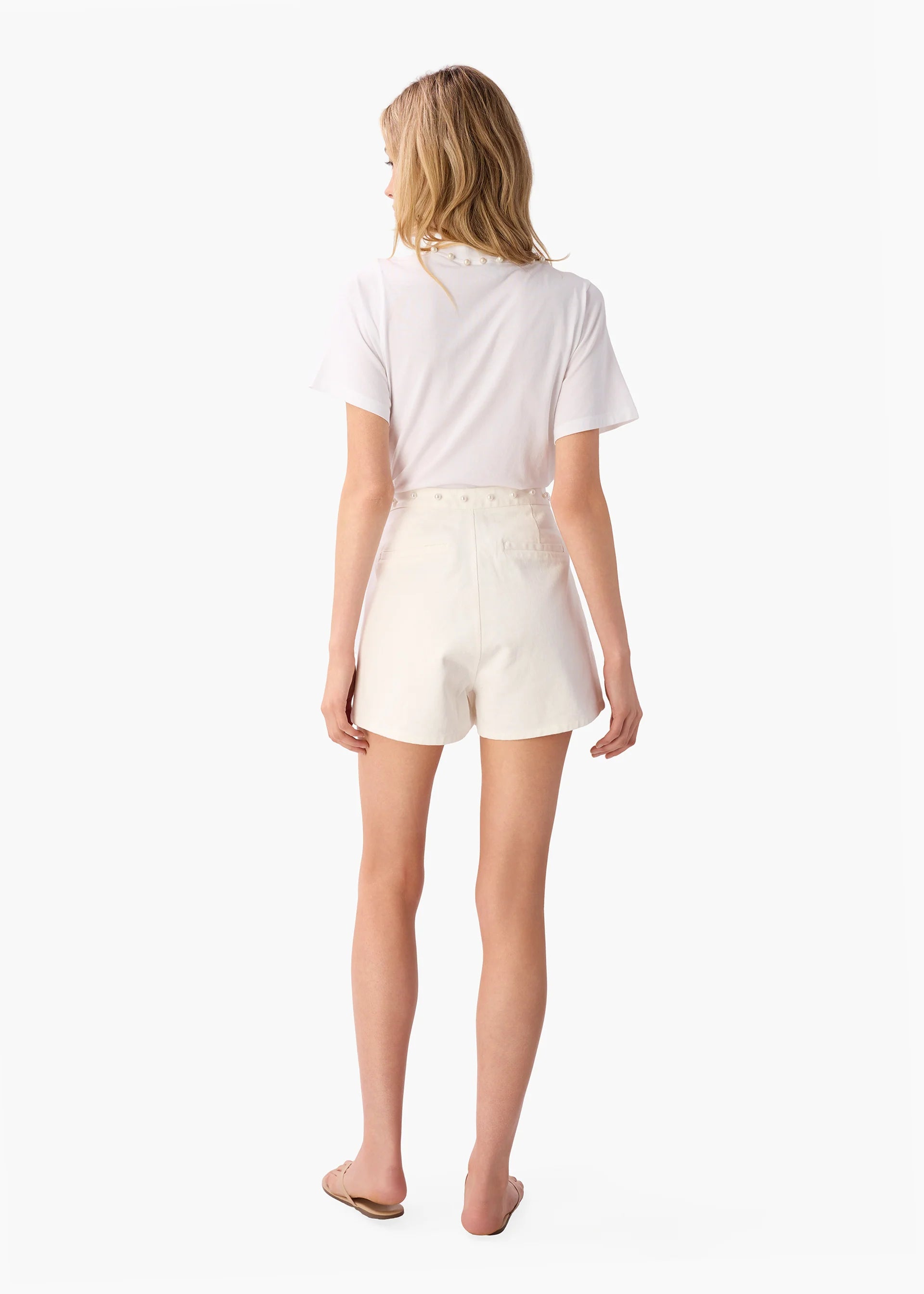 Woman wearing a white t-shirt and cream shorts on a white background