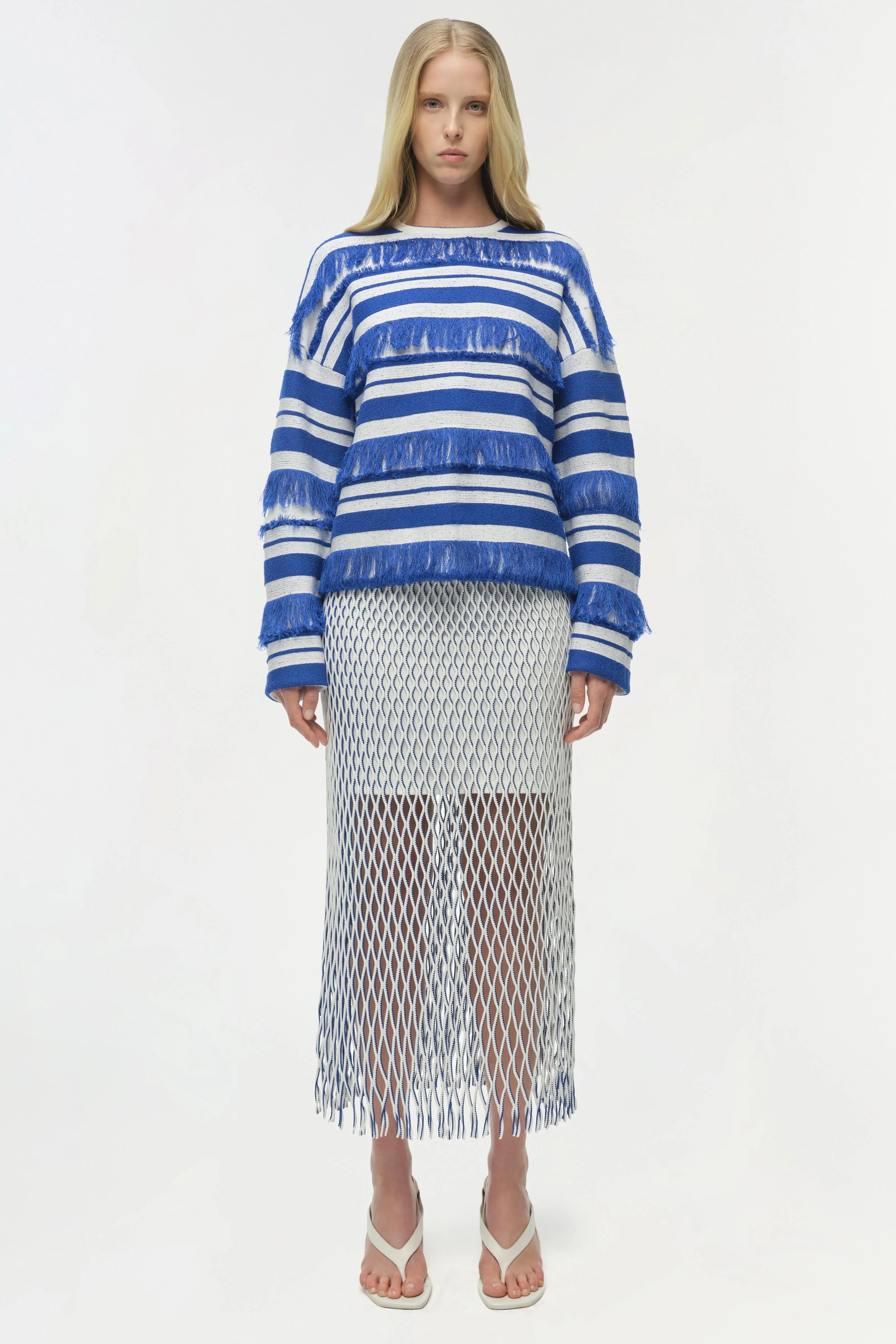 Woman wearing a blue and white striped sweater with a sheer net skirt on a white background