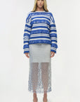 Woman wearing a blue and white striped sweater with a sheer net skirt on a white background