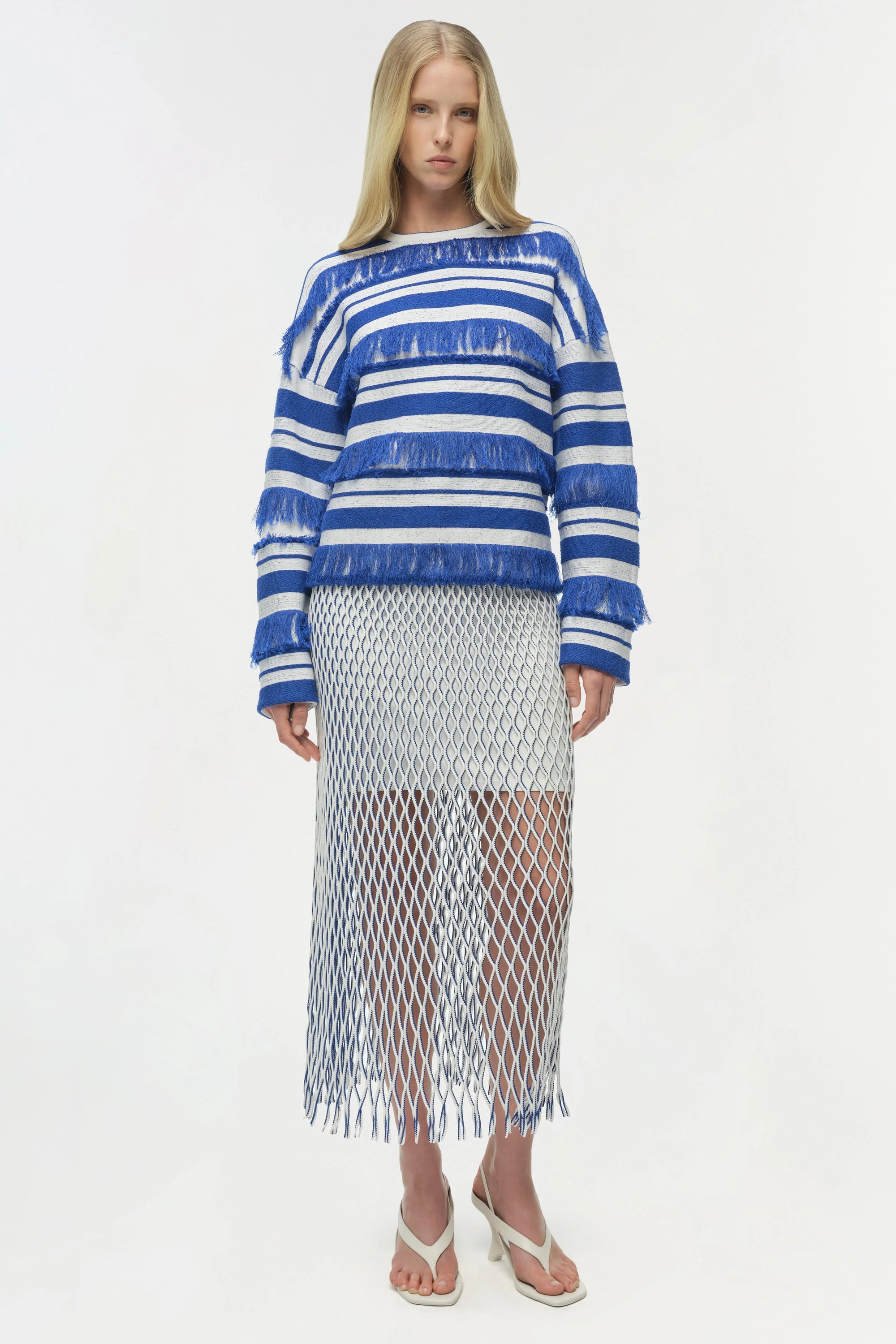 Woman wearing a blue and white striped sweater with a fishnet skirt on a white background