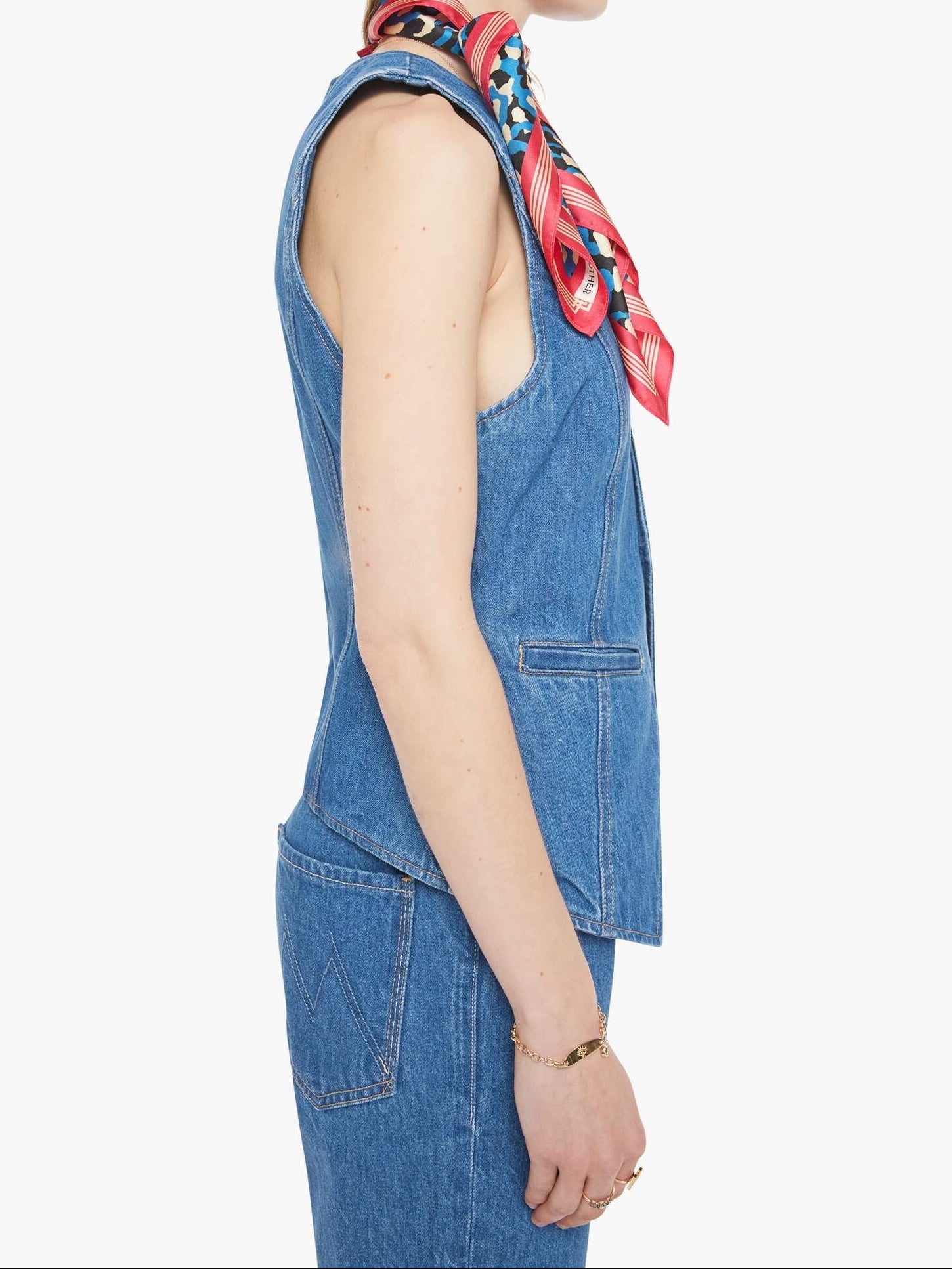 Woman wearing a blue denim outfit with a colorful scarf on a white background, side