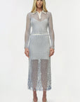 Woman wearing a long-sleeve, patterned dress on a white background