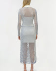 Woman wearing a long, sheer fishnet dress with a white background