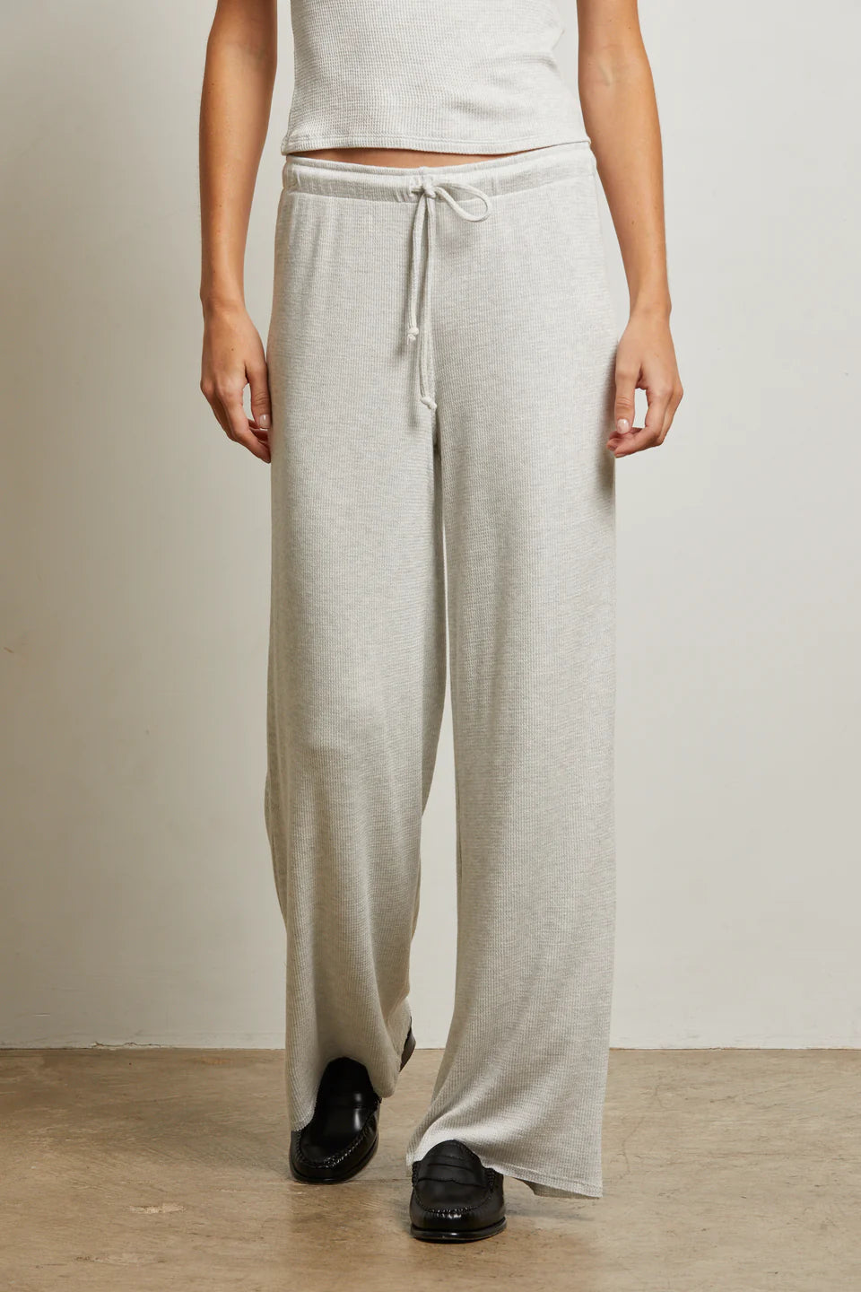 Person wearing light gray sweatpants with a plain background front view