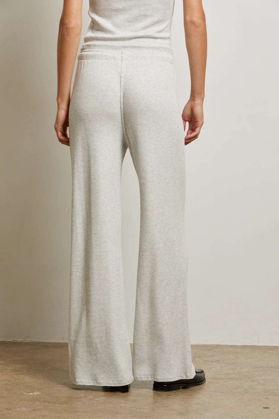 Person wearing light gray wide-leg pants against a neutral background back view