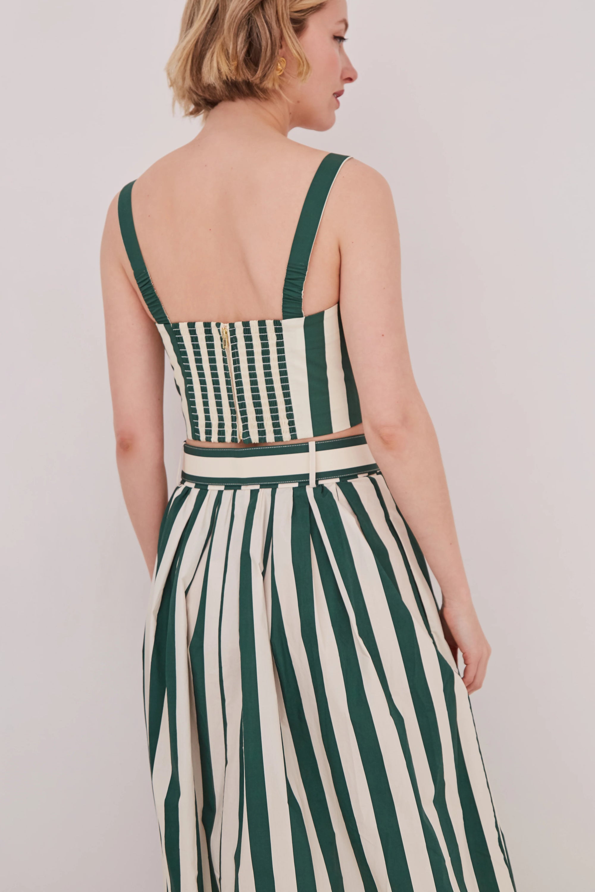 Woman wearing a green and white striped matching set against a plain background