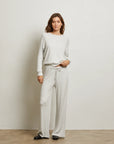 Woman wearing a light gray sweater and pants against a white background front view