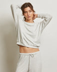 Woman wearing a light gray sweatshirt and pants against a plain background front view