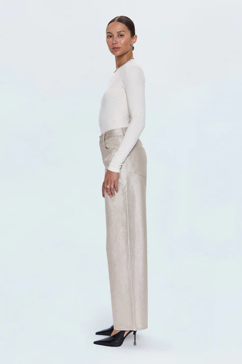 Woman wearing a white long-sleeve top and beige pants on a light blue background