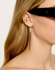 Gold shell earring and dangling earrings worn by a person with long blonde hair.