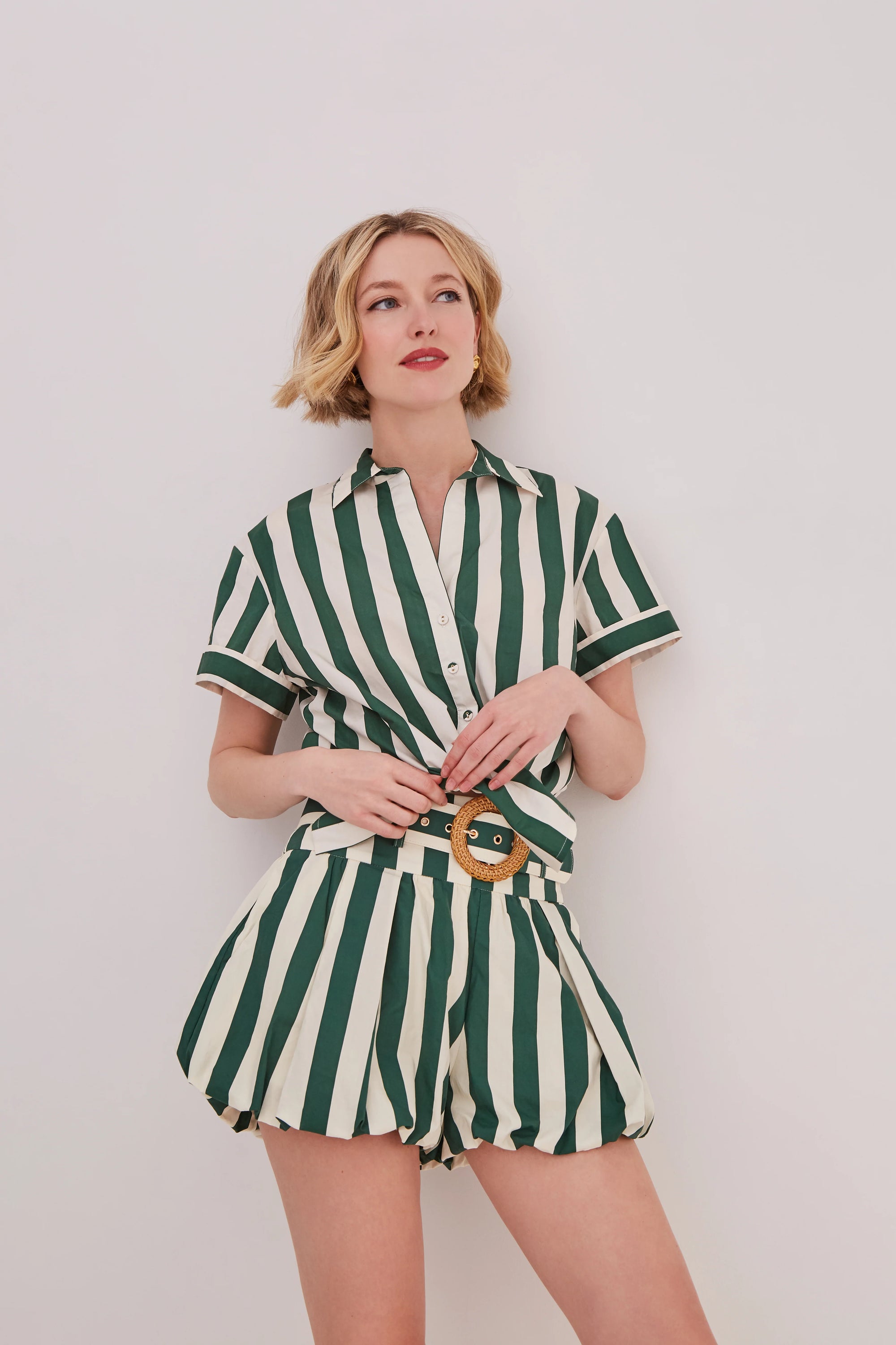 Woman wearing a green and white striped outfit against a plain background
