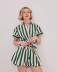 Woman wearing a green and white striped outfit against a plain background