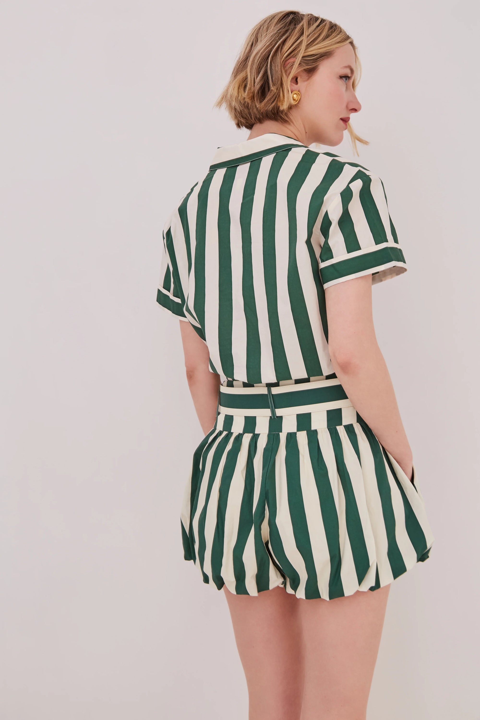 Person wearing a green and white striped outfit on a plain background