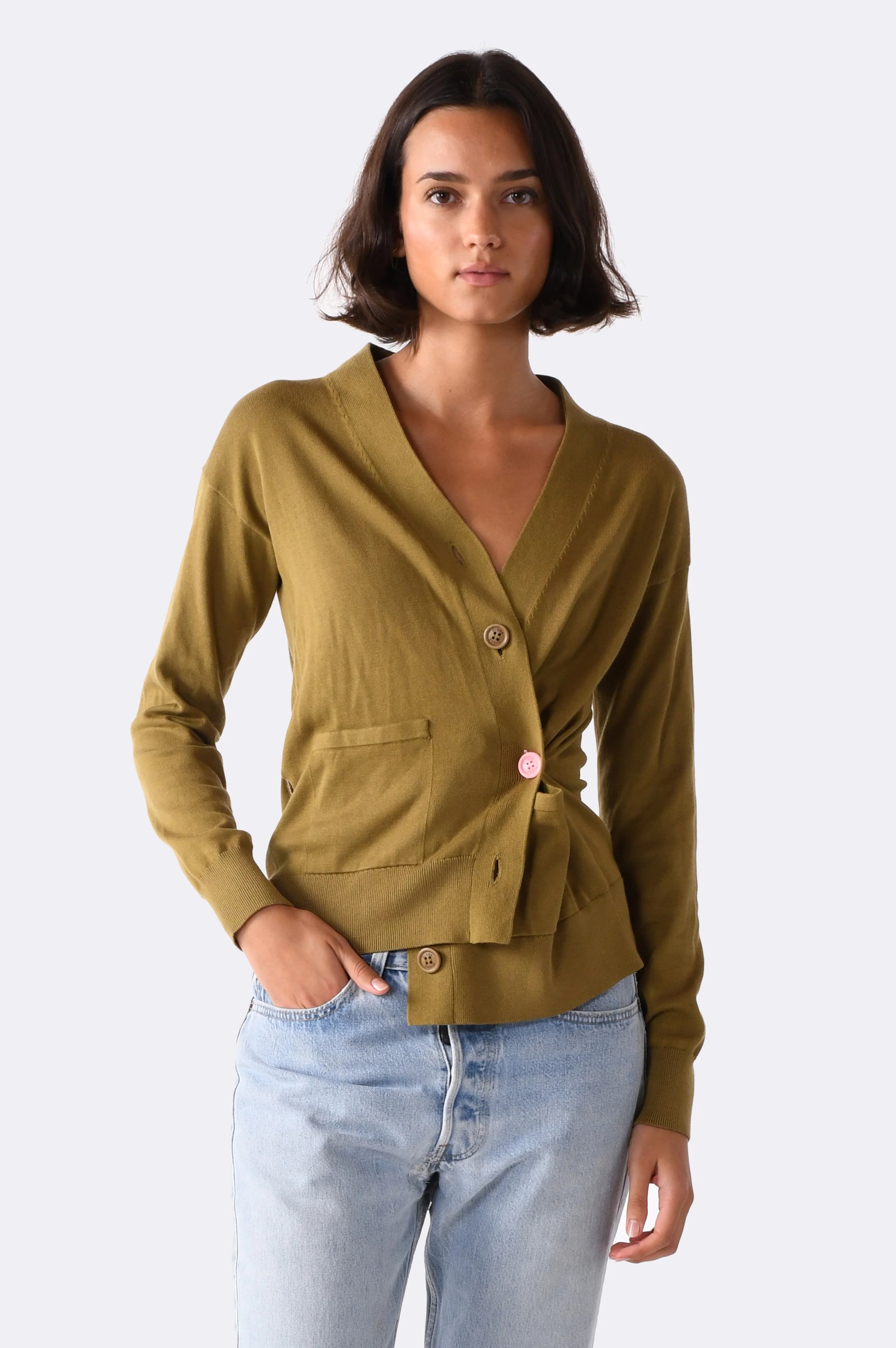 Woman wearing a green blazer and light blue jeans on a white background