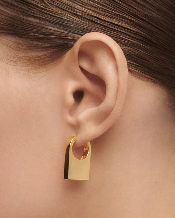 Gold hoop earring worn by a person with brown hair.