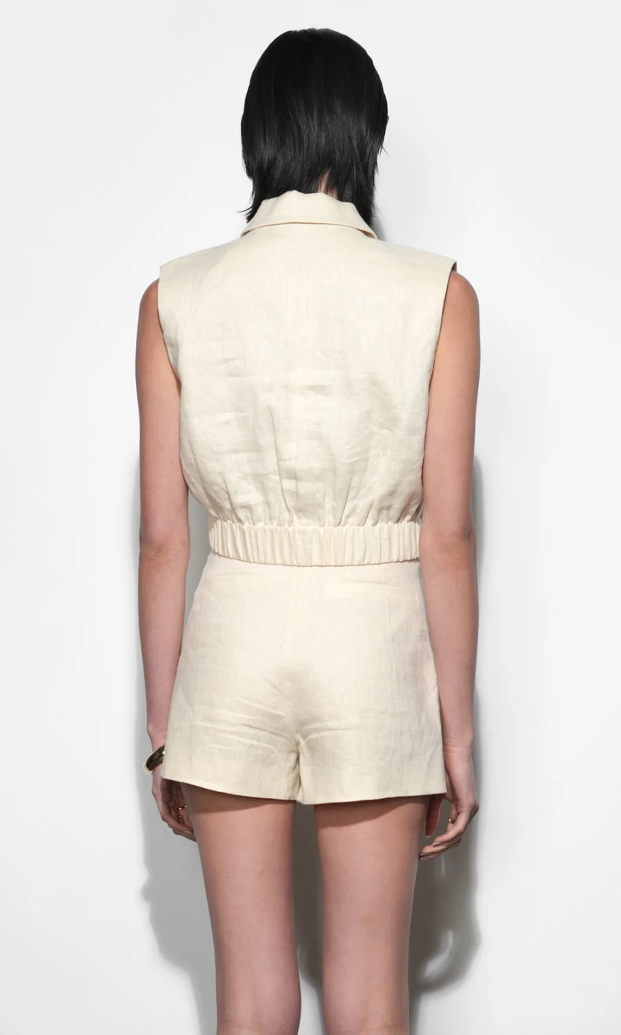 Person wearing a beige sleeveless top and shorts set on a white background