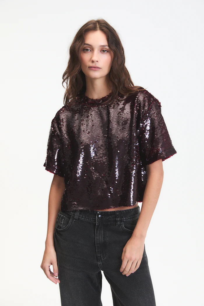 Woman wearing a sequin top and black pants on a white background