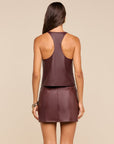 A woman shown from the back wearing a sleeveless dark plum-brown top and matching mini skirt set against a plain beige studio background.