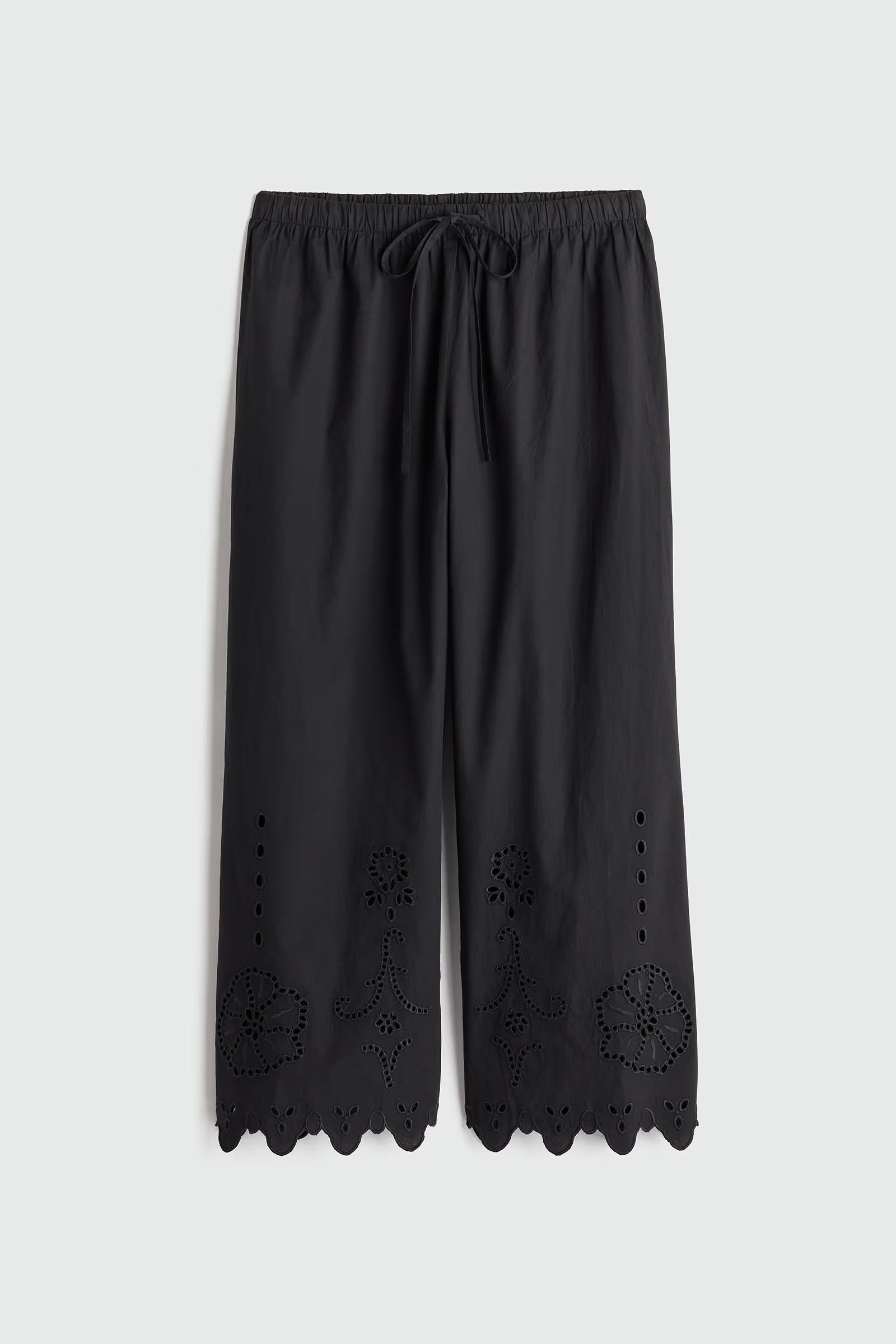 Black pants with scalloped hem on a light gray background