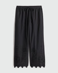 Black pants with scalloped hem on a light gray background