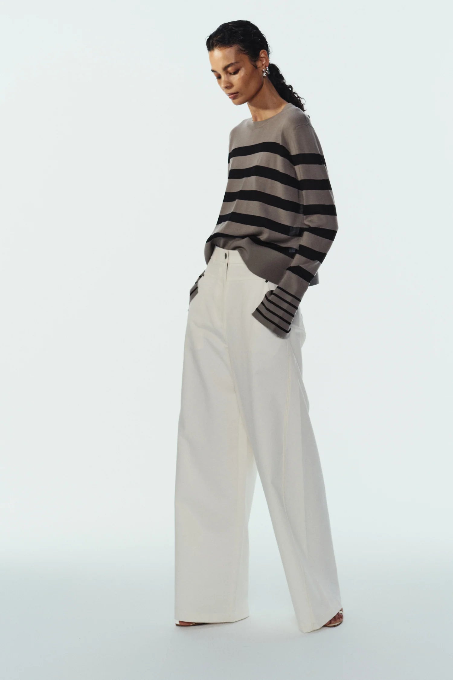 model wearing stripe sweater and white pants on a white background
