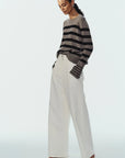 model wearing stripe sweater and white pants on a white background