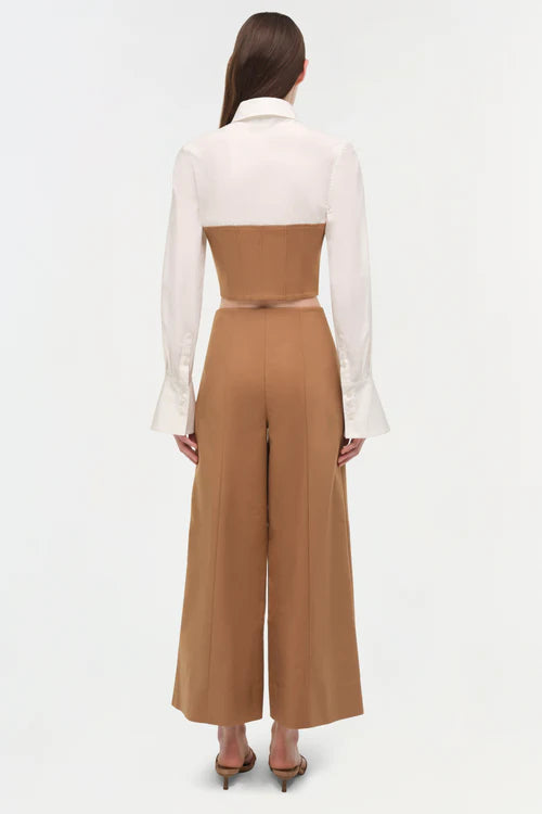 Woman wearing a white blouse and brown jumpsuit on a white background