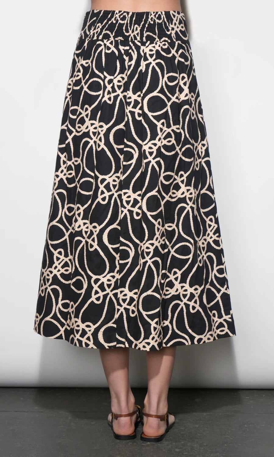 Black skirt with beige abstract pattern worn by a person on a white background