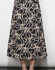 Black skirt with beige abstract pattern worn by a person on a white background