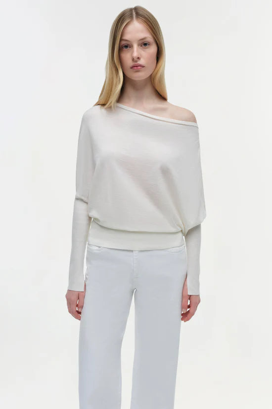 Woman wearing a white off-shoulder top and light gray pants on a white background