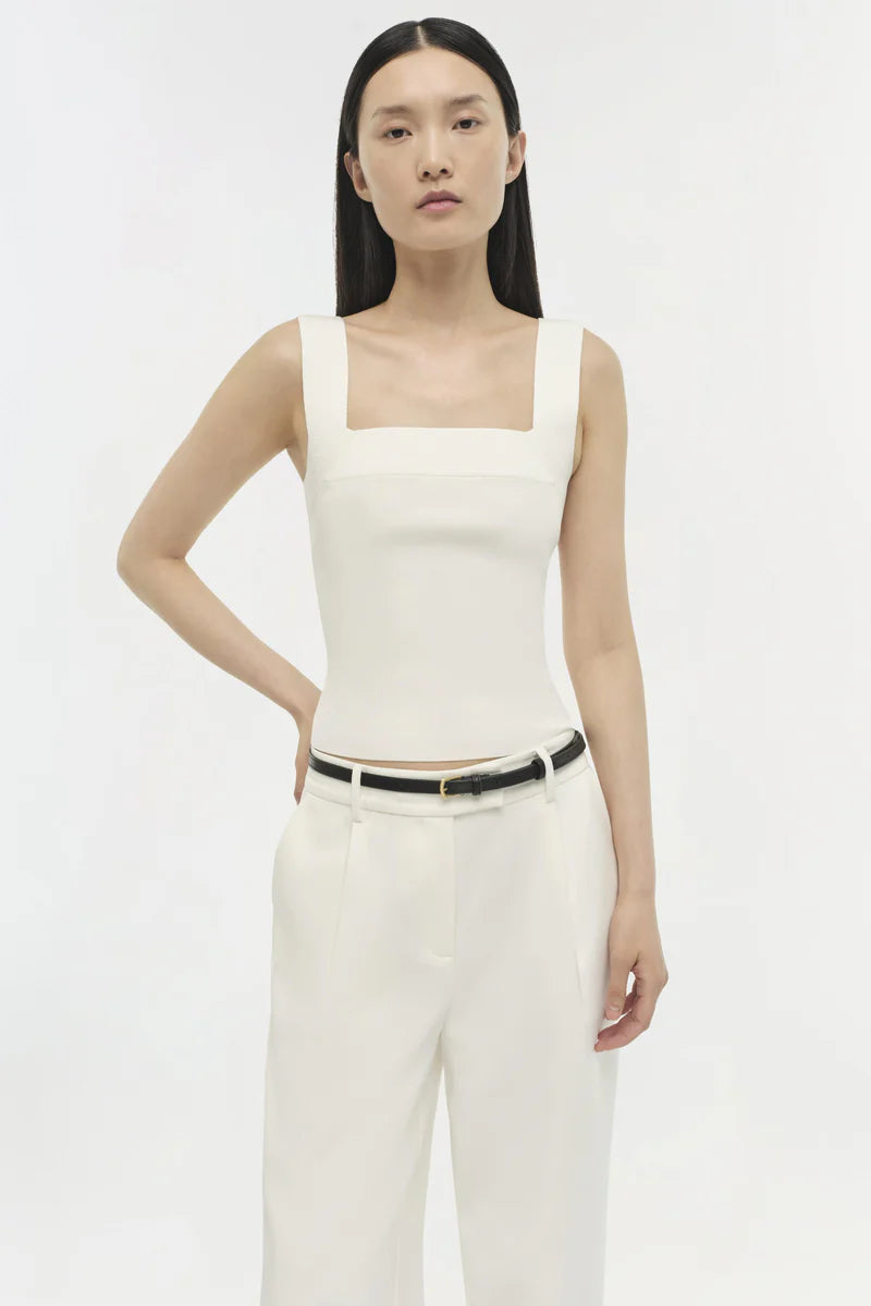 Woman wearing a white sleeveless top and pants on a white background